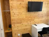 Armario abierto con perchas y caja fuerte junto al televisor y el escritorio de la habitación